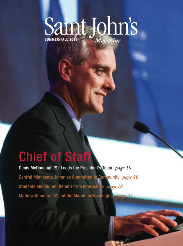 A man in a suit stands at a podium with a microphone, speaking on stage against a blue backdrop. The text overlay reads "Saint John's Magazine" with articles on various topics. The issue is Summer/Fall 2013.